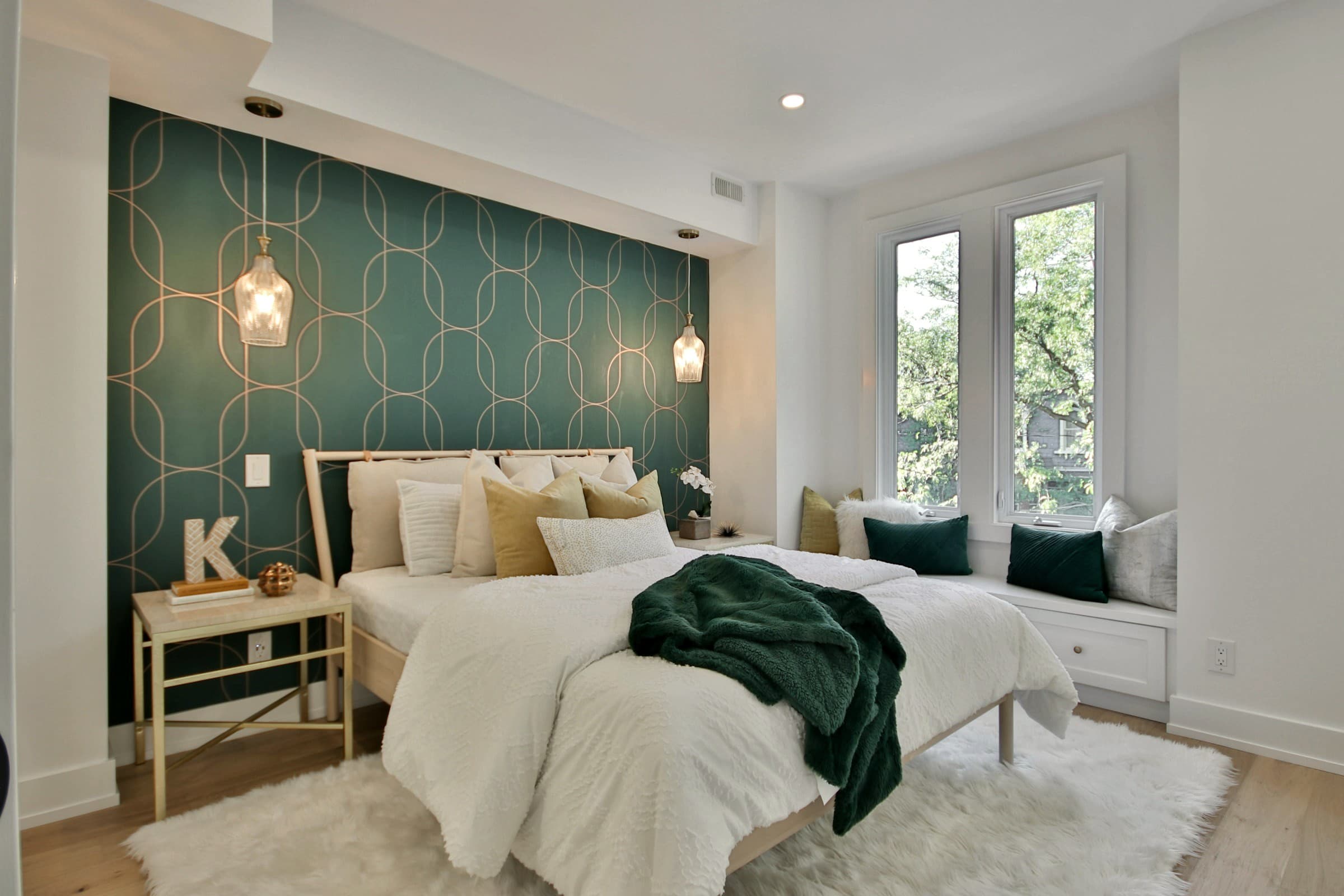 Principal bedroom with a deep emerald panelled headboard wall and brass pendant lights