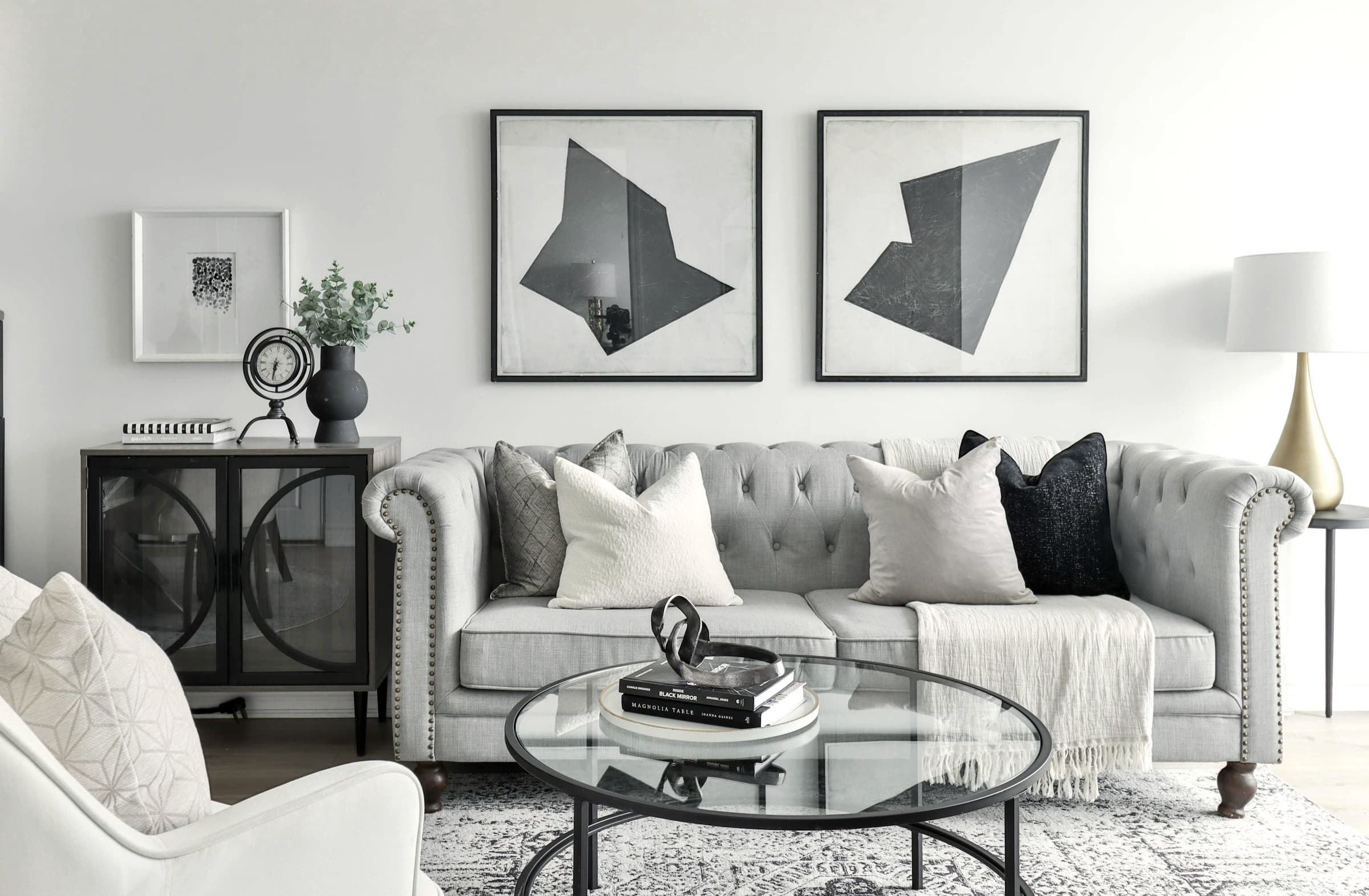 Formal living room with tufted seating and paired abstract artworks